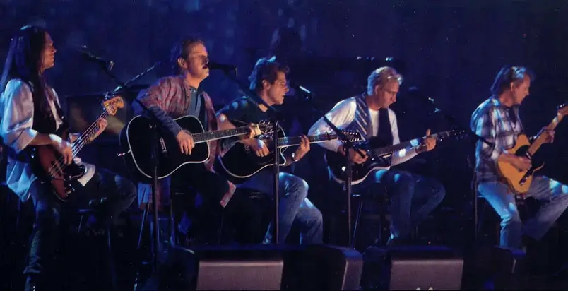 A imagem mostra a banda de rock Eagles tocando a música Hotel California ao vivo. Eles são, da esquerda para a direita, Timothy B. Schmit, Don Henley, Glenn Frey e Joe Walsh. Eles têm instrumentos musicais nas mãos. A imagem serve para ilustrar o artigo Eagles: Além de Hotel California, que fala sobre outros sucessos da banda.