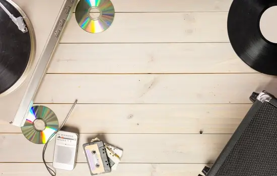 Disco de vinil, CDs e fitas cassete em uma mesa de madeira