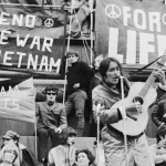 Jovens nos anos 60 em um protesto com um violão cantando rock como crítica social