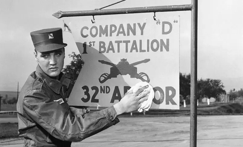 Elvis segurando uma placa do batalhão do exército