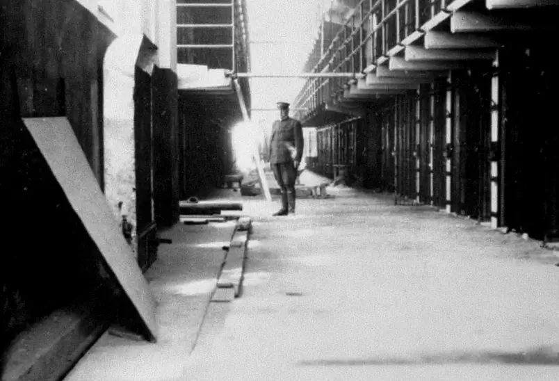 Foto interna da prisão de Alcatraz, com um carcereiro em um corredor
