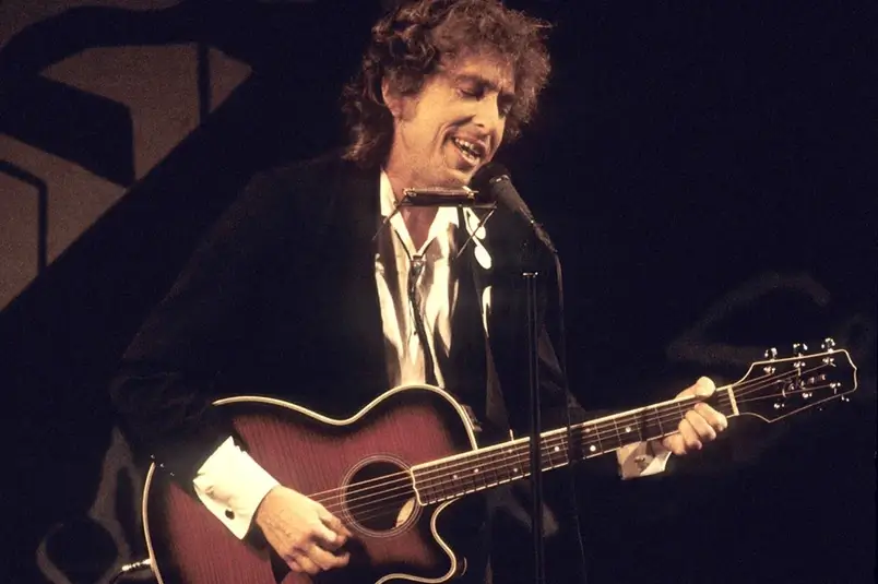 Bod Dylan tocando violão em um show. Ilustra o artigo sobre os covers de Bob Dylan